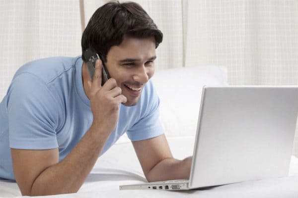 man on mobile phone with laptop