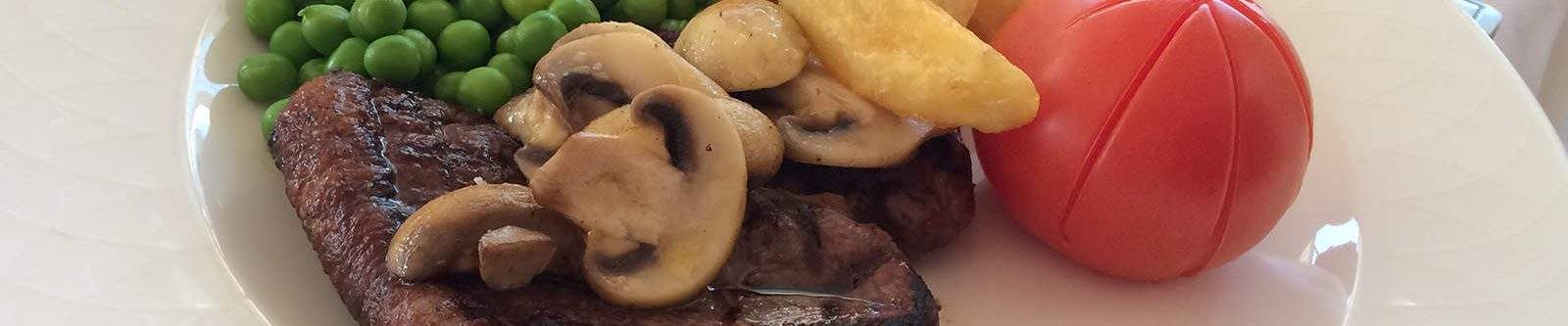 steak and chips with mushrooms, peas and tomato