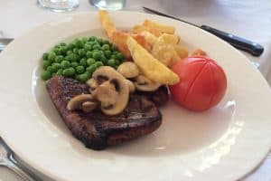steak and chips with mushrooms, peas and tomato