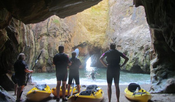 people standing in a cave with kayaks